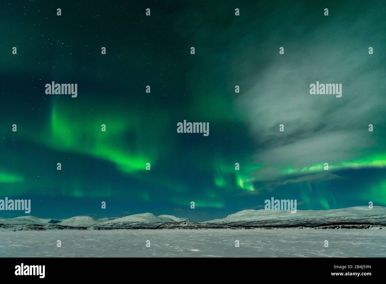 Schweden, zugefrorener See (Torneträsk) mit Polarlicht und mondbeschienenen Wolken Stock Photo