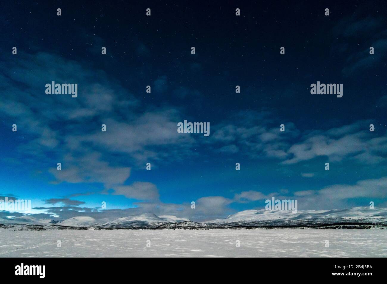 Schweden, Lappland, Abisko, zugefrorener See (Torneträsk) im Mondschein, Nachthimmel mit schwach beginnendem Polarlicht Stock Photo