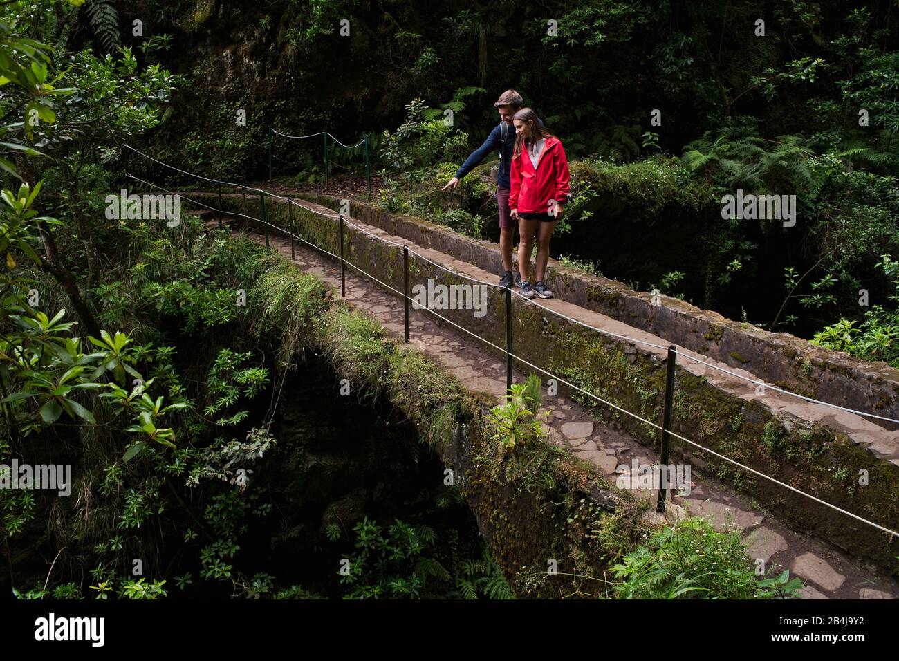 Zwei Wanderer, Paar, stehen auf Aquädukt am Wanderweg PR 9 Caldeirao Verde, Queimadas, Caldeirao do Inferno, Regenwald, entlang eines Levada, Insel Ma Stock Photo