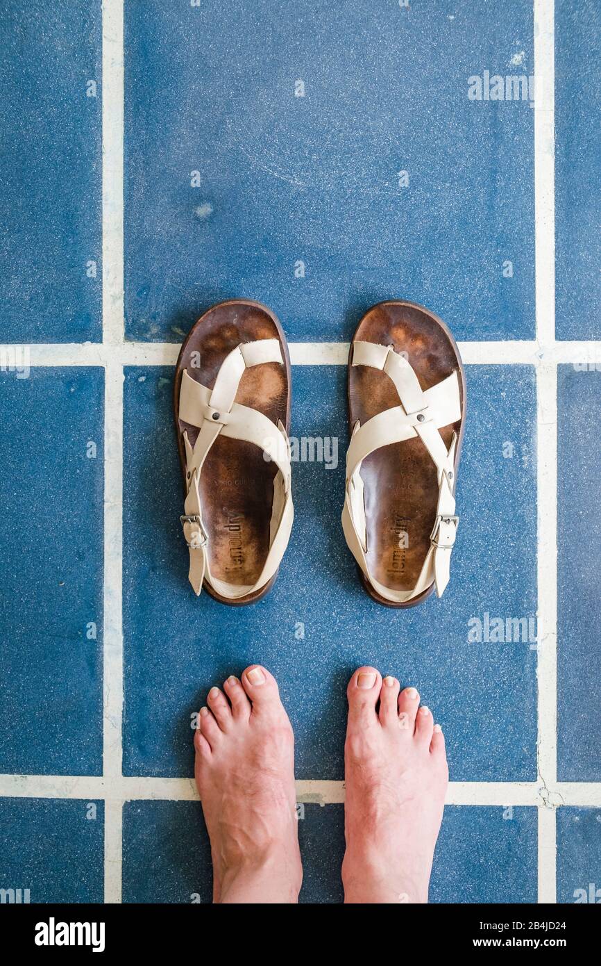 Feet in sandals are standing on blue tiles Stock Photo