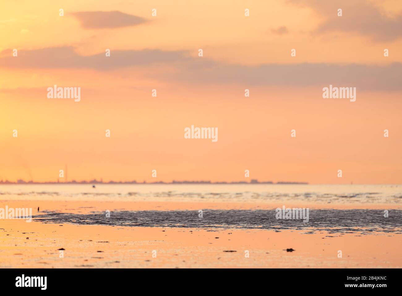 Europa, Deutschland, Niedersachsen, Otterndorf. Sonnenuntergang über der Elbmündung vor Cuxhaven. Im Vordergrund spiegelt sich das Abendlicht im Watte Stock Photo