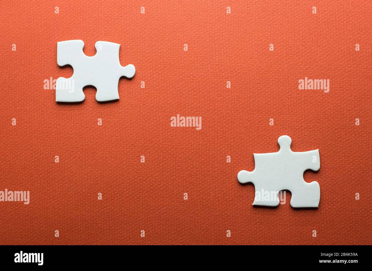two separate white puzzle pieces on an orange background Stock Photo