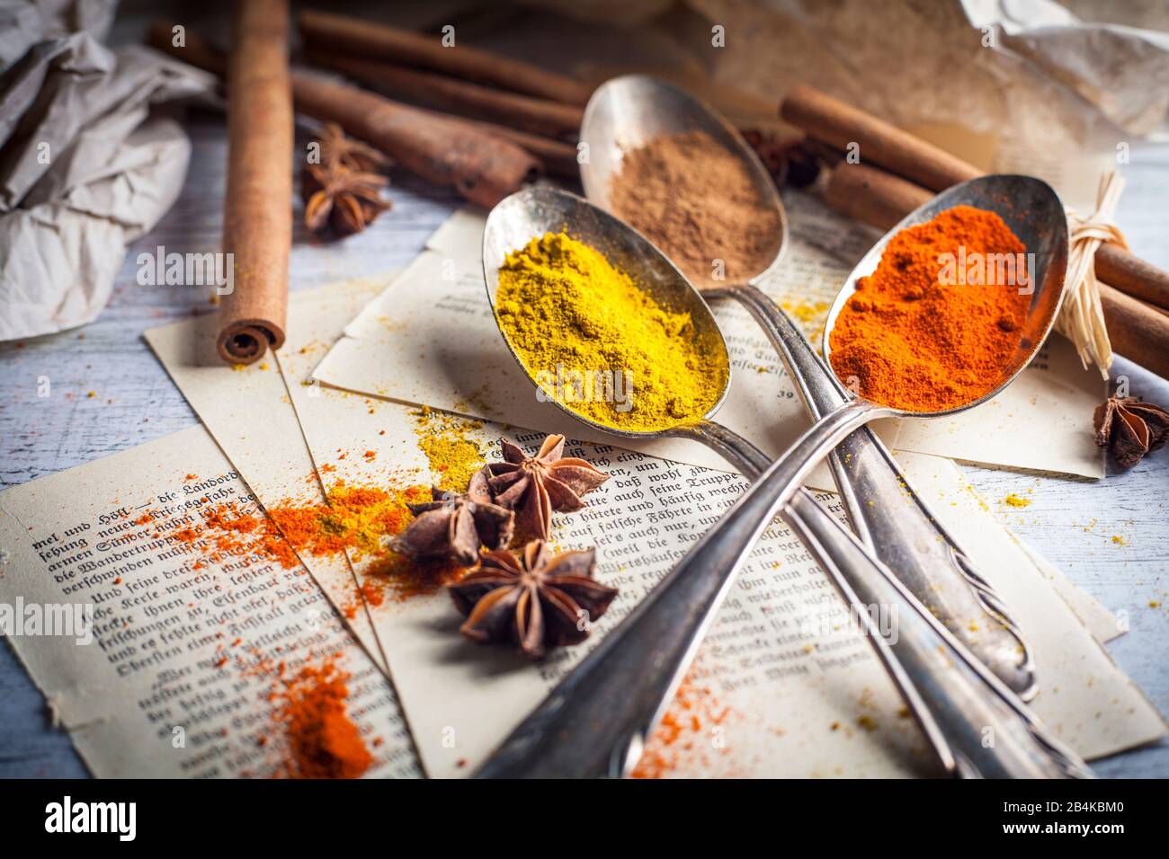 Spices on silver spoons on old book pages Stock Photo