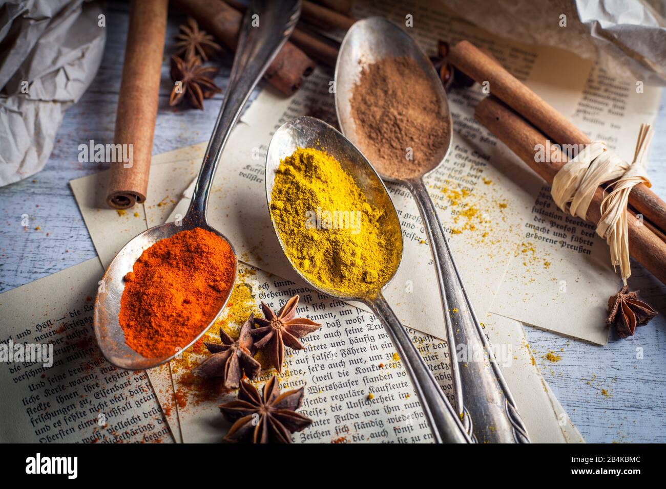 Spoon with spices, anise and cinnamon on old book pages Stock Photo