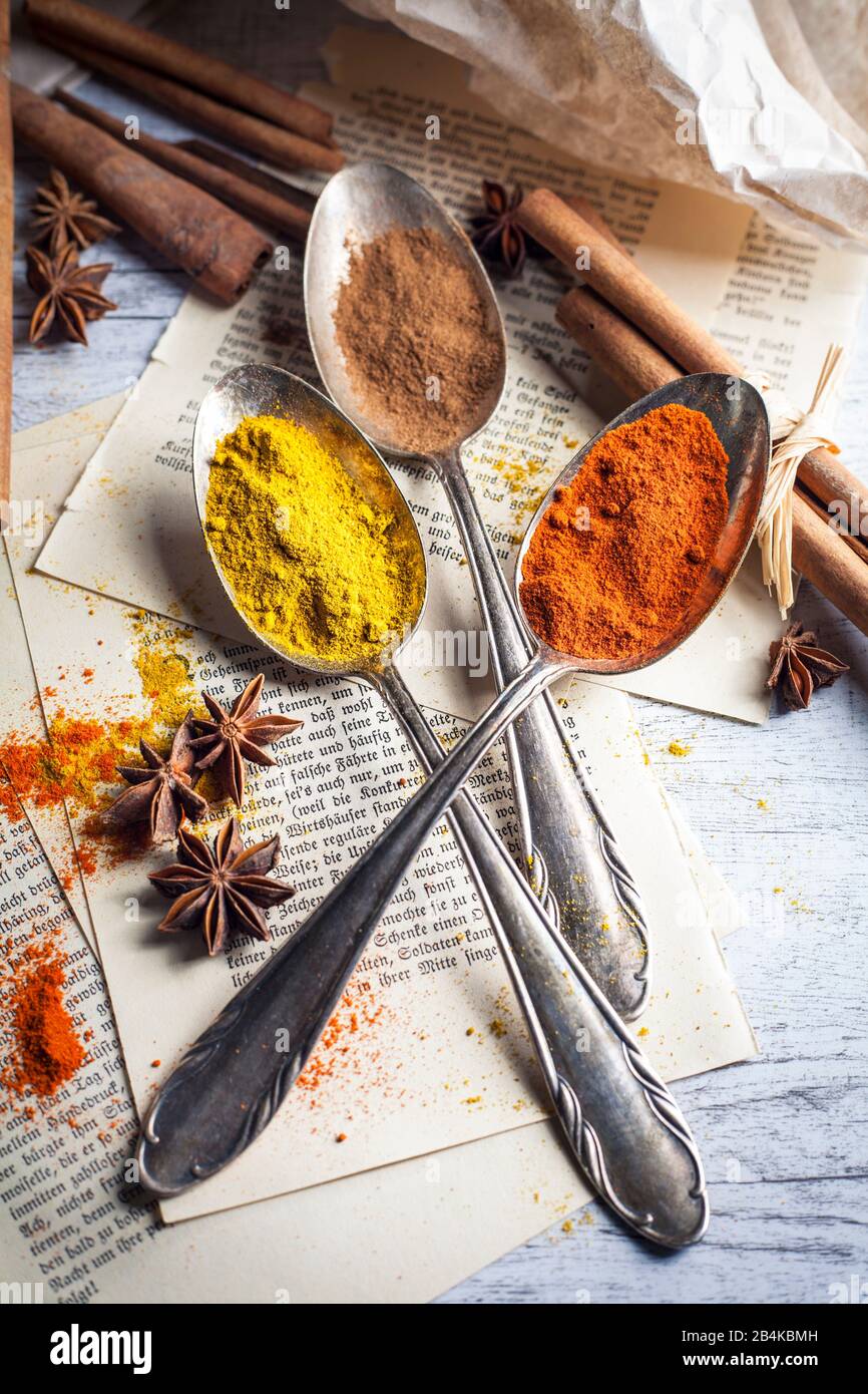 Spoon with spices, anise and cinnamon on old book pages Stock Photo