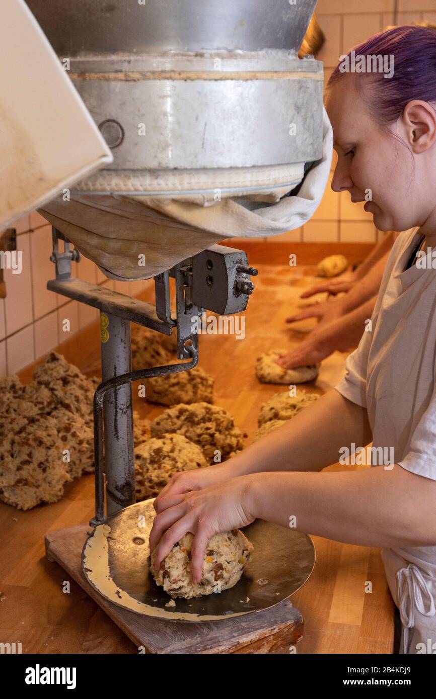 Weiblicher Bäcker-Lehrling, 20 - 30 Jahre, lila Haare, wiegt Teig für die Zubereitung von Weihnachtsstollen ab. Stock Photo