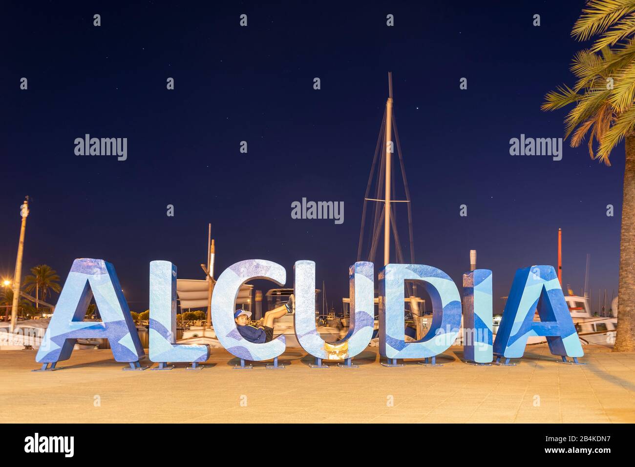Spain, Mallorca, Allcúdia, boy lies in the letter C of the lettering Allcúdia, Port de Alcúdia Port in the north of the Mediterranean island of Mallorca. Stock Photo