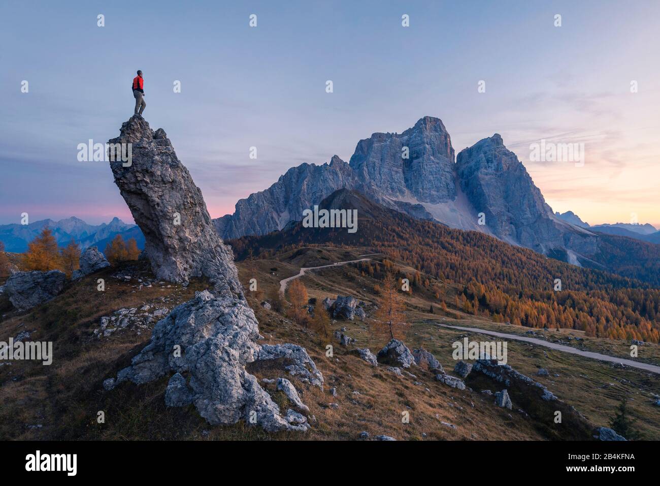 lonely man standing on a rock facing the north wall of mount pelmo, dolomites, san vito di cadore, belluno, veneto, italy Stock Photo