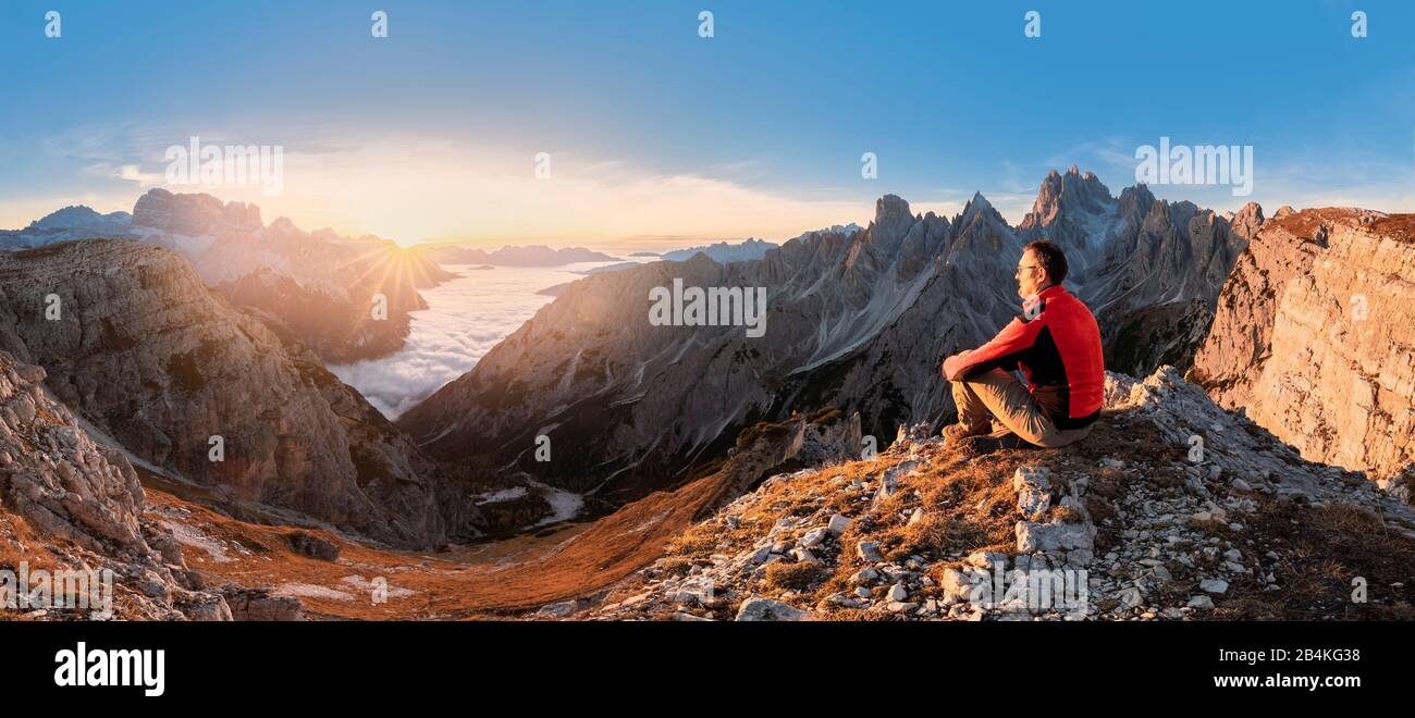 Hiker admiring the Dolomites at sunrise in front of Cadini di Misurina, Auronzo di Cadore, Belluno, Veneto, Italy Stock Photo