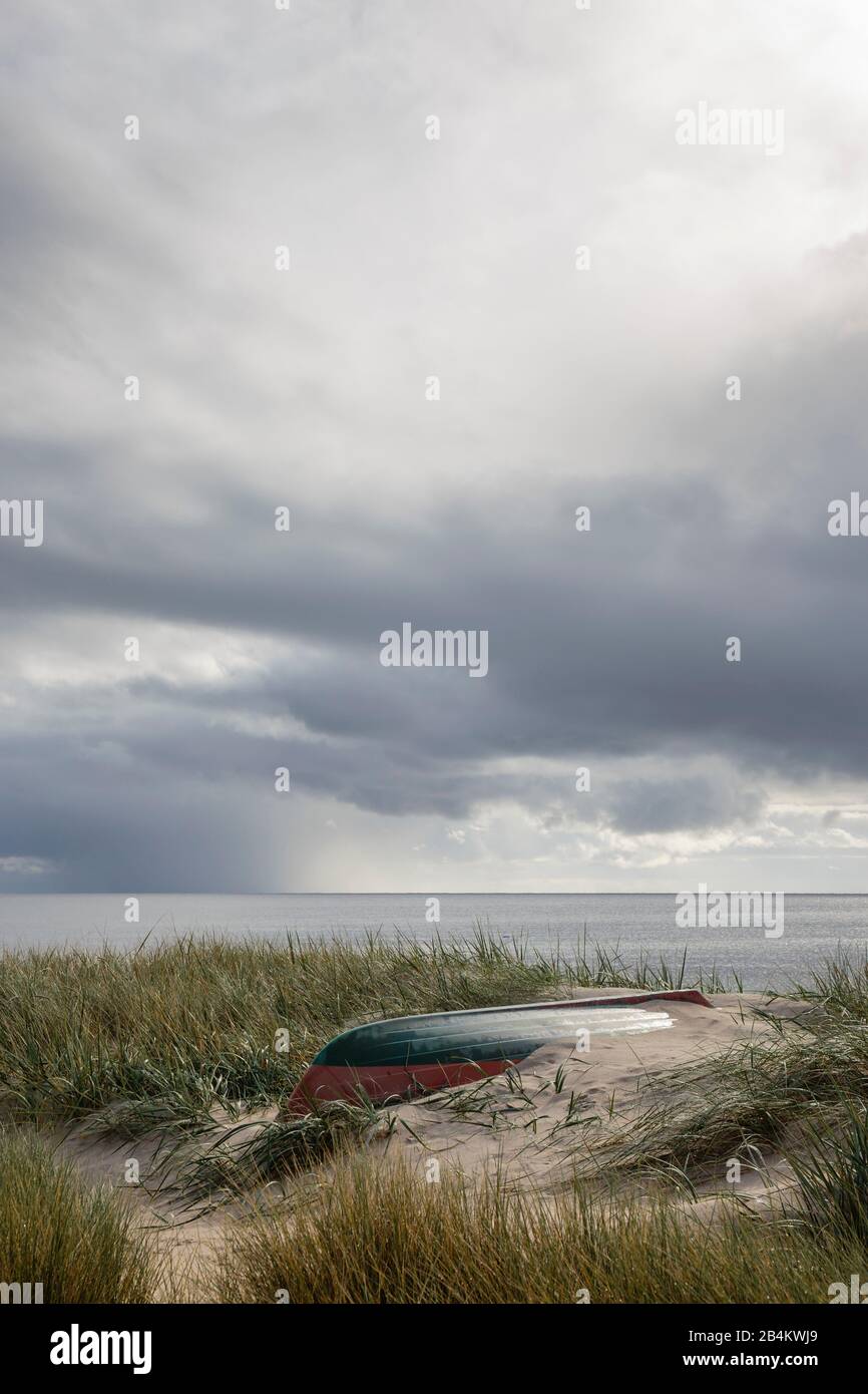 Europa, Dänemark, Bornholm. Zwischen dem Gras am Strand von Vester Sømarken liegt ein altes Ruderboot. Stock Photo