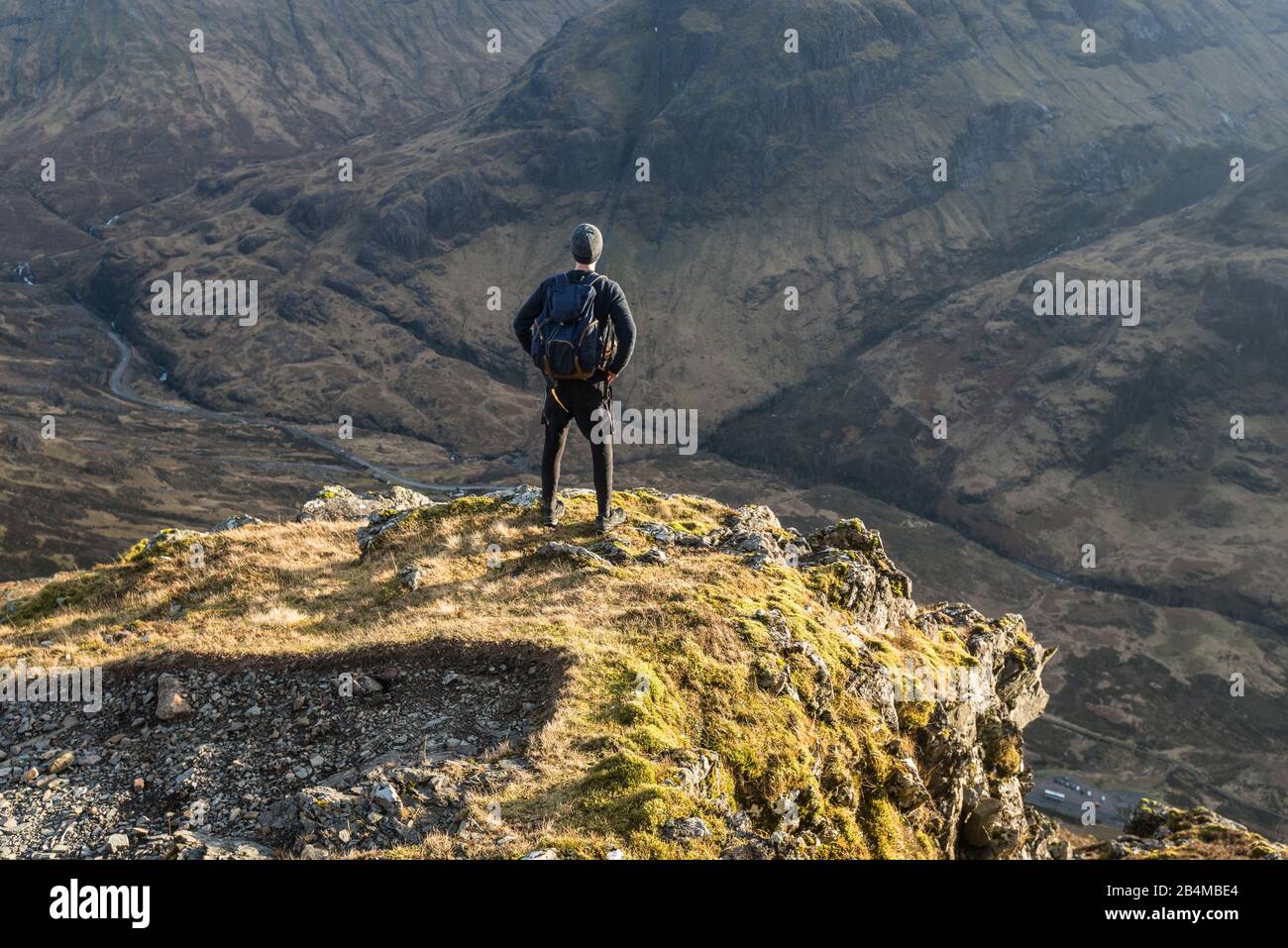 Großbritannien, Schottland, Highlands, Glencoe, Junger Mann blickt von Felsvorsprung ins Tal Richtung Three Sisters Stock Photo
