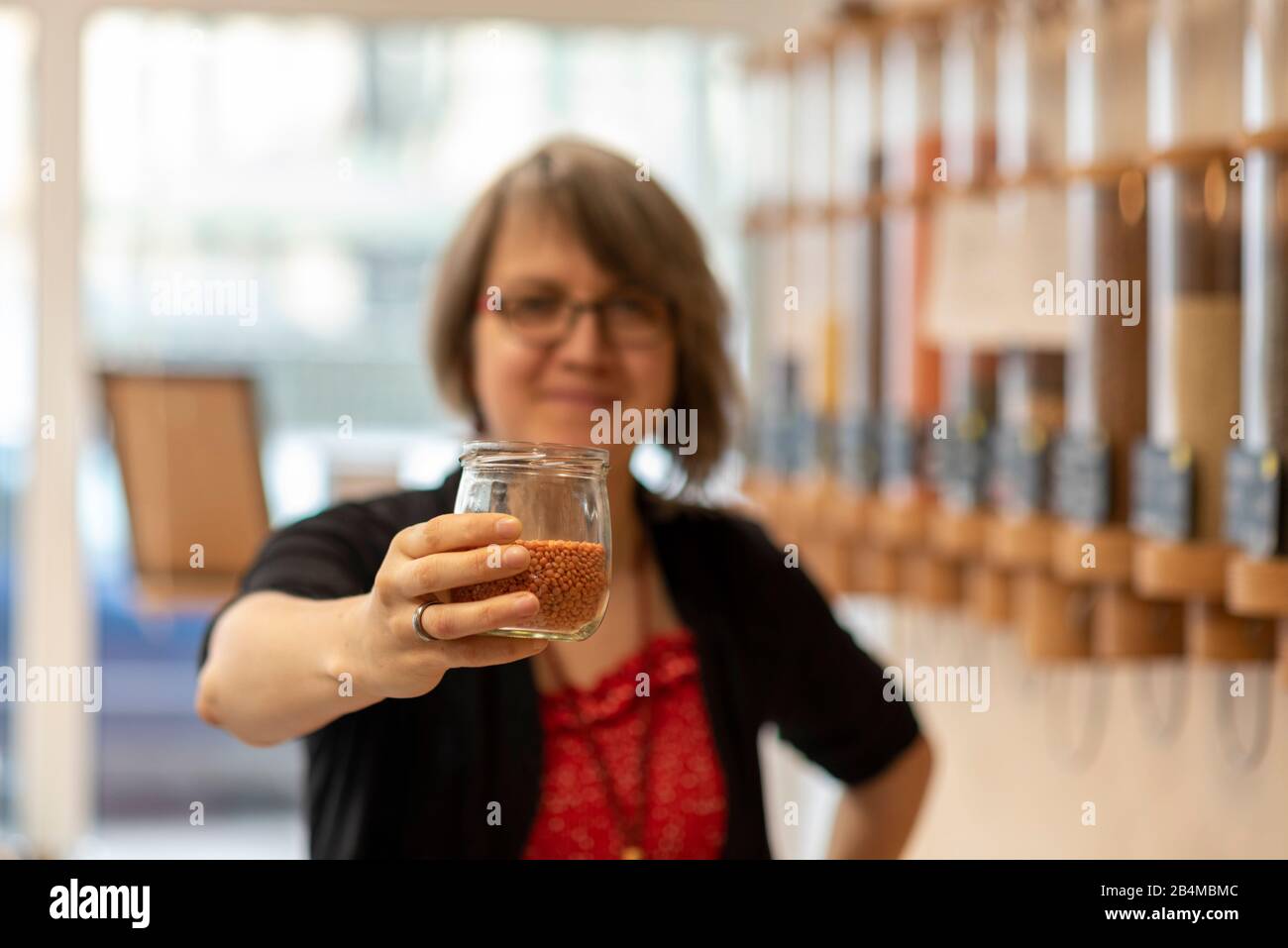 Eine Frau hält ein Glas mit Linsen in der Hand, Detail aus einem Unverpacktladen. Stock Photo