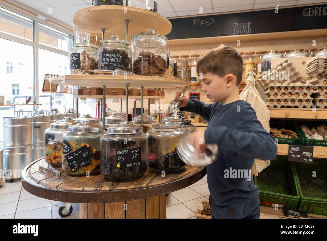 Eine Junge füllt sich in einem Unverpacktladen Süßigkeiten ab. Stock Photo