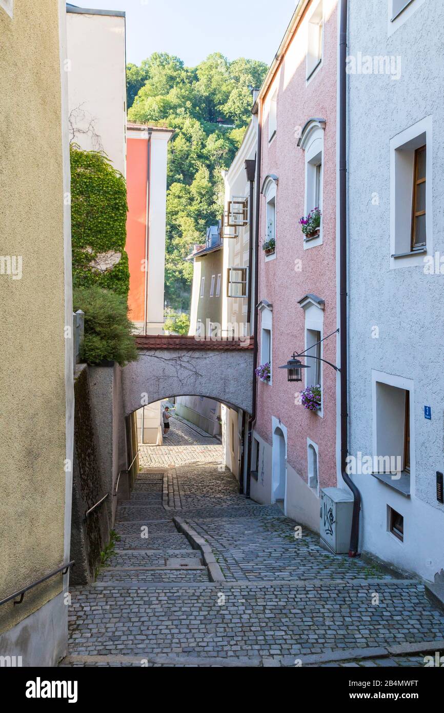 Quaint narrow cobbled lane in Passau, Bavaria, Germany in summer with arch between the buildings and view to trees Stock Photo
