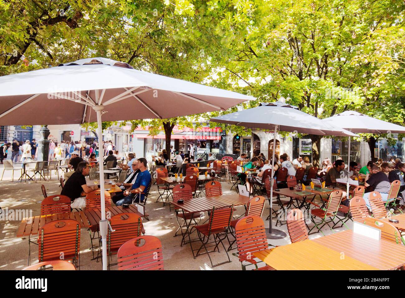 Guests sit in a typical street cafe under green trees. Besançon is a city in eastern France. Department of Doubs. Stock Photo