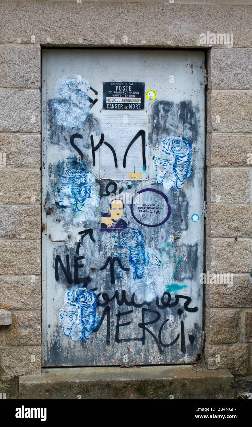 Door in wall made of stone blocks sprayed with political grafitti. Tréguier is a commune in the Côtes-d'Armor department in Brittany; Tréguier is the historic capital of the Trégor. Stock Photo