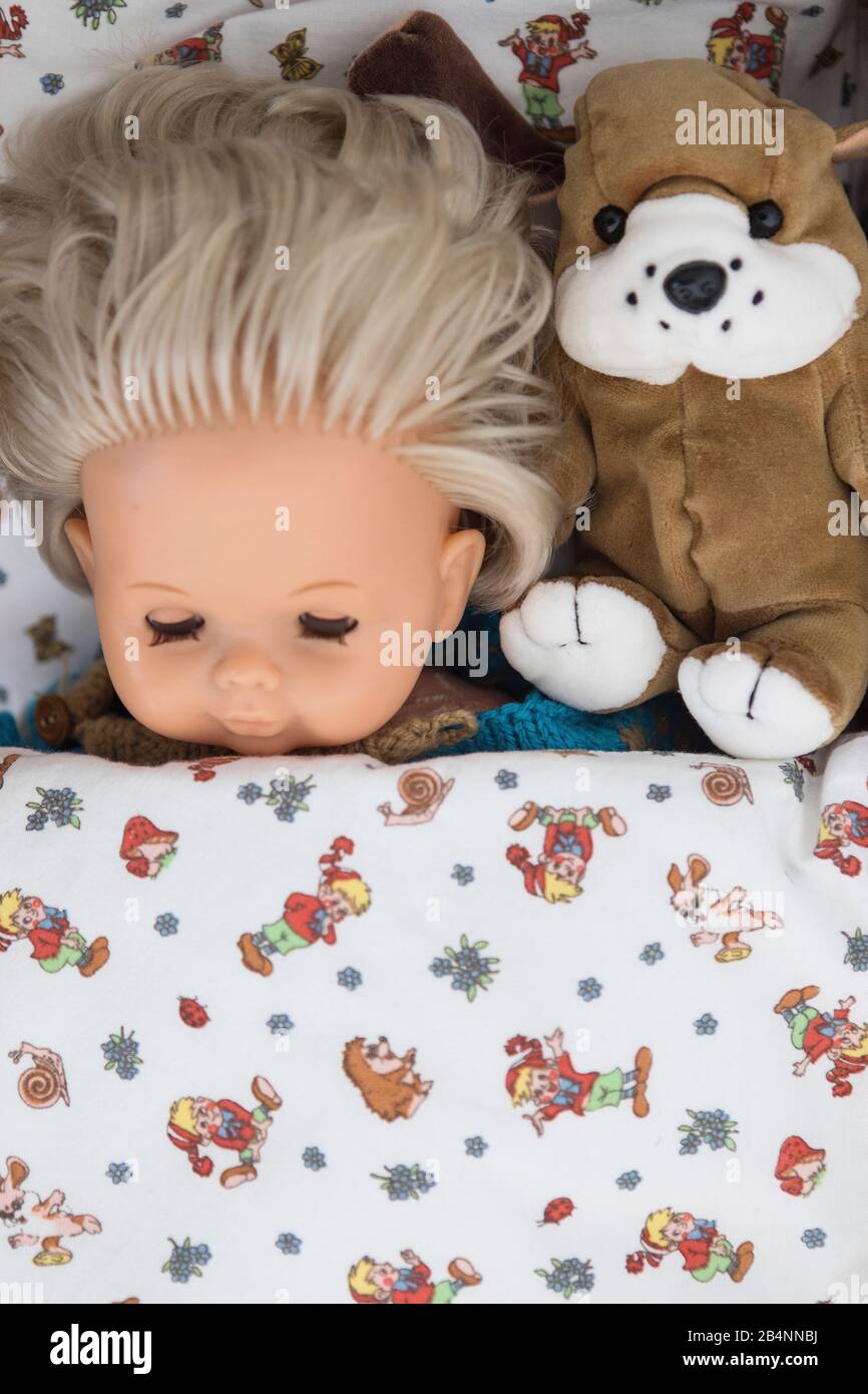 Doll and soft toy in a doll's bed Stock Photo
