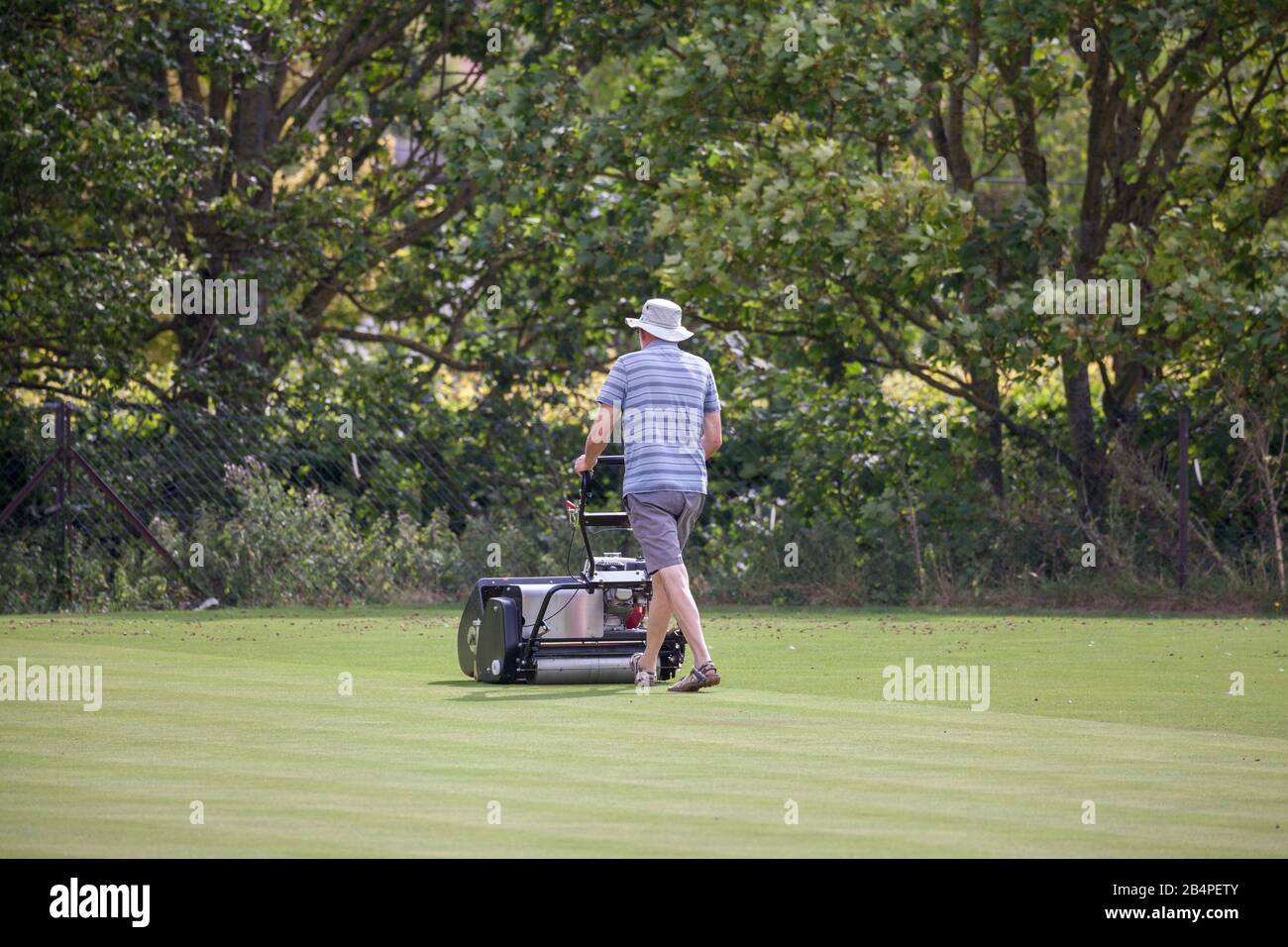 Man mowing the lawn at a bowling green Stock Photo
