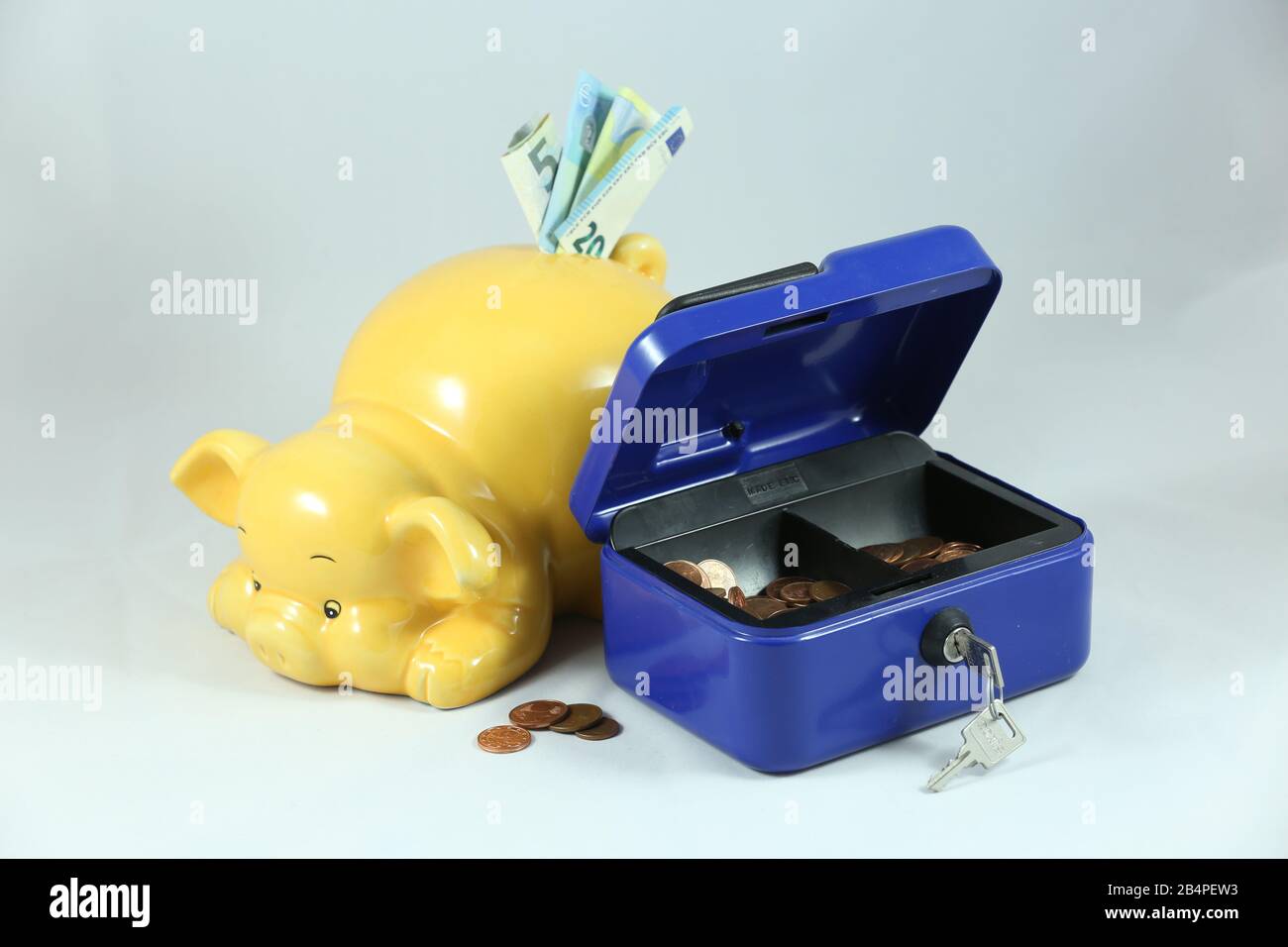 Yellow friendly piggy bank with money and blue cash box Stock Photo