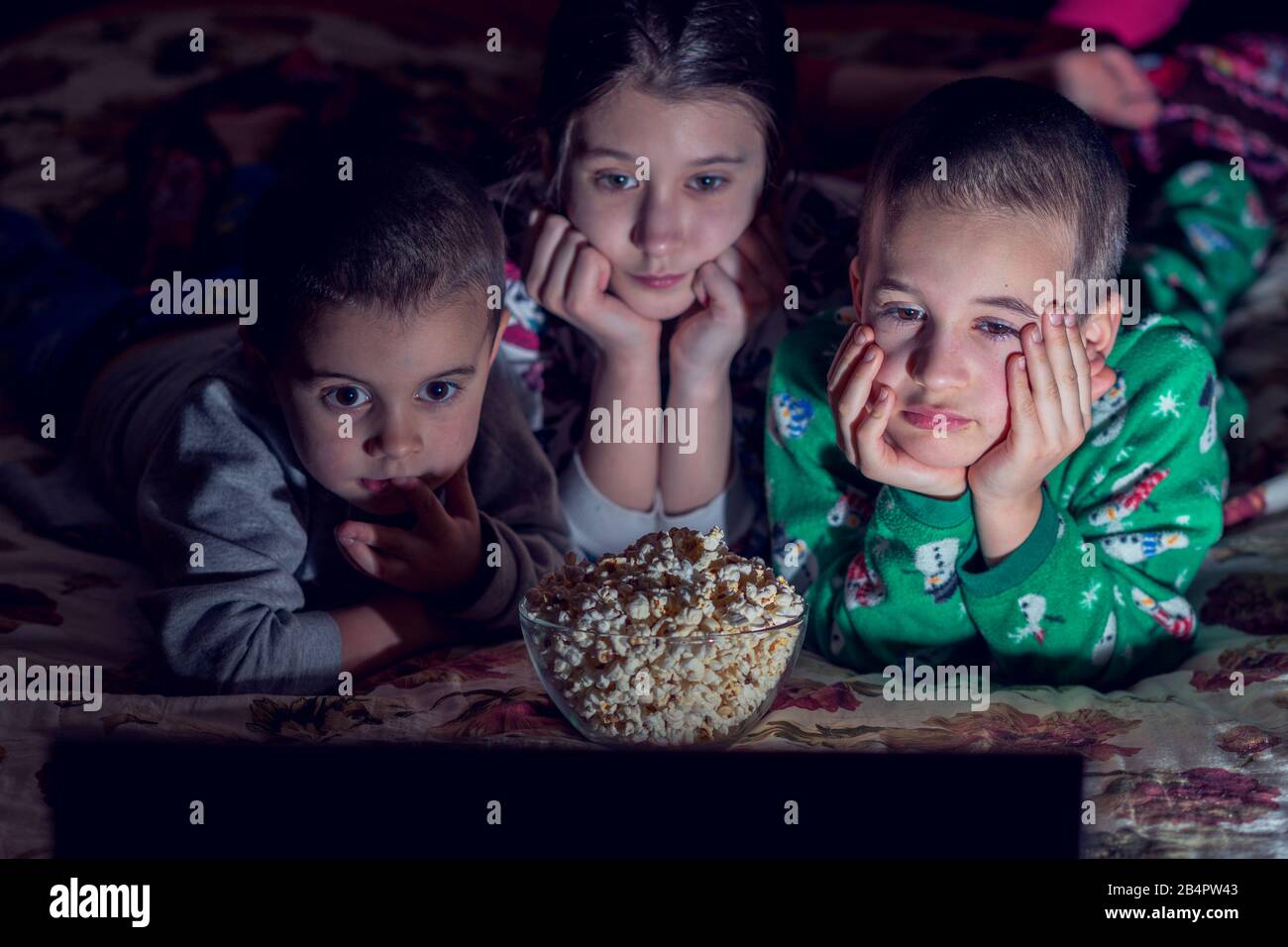 Children looking at laptop with cartoons showing before sleeping in bed