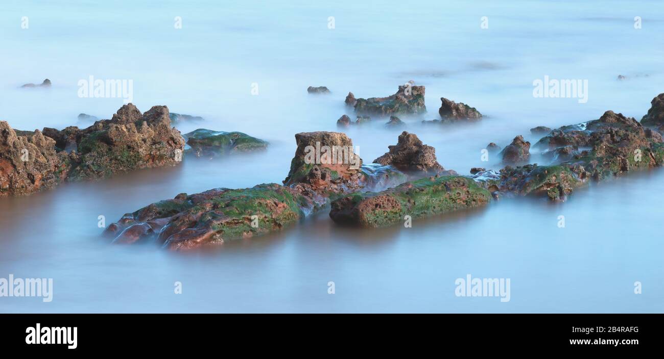 Rocks on the beach near town of Sidmouth taken with long exposure Stock Photo