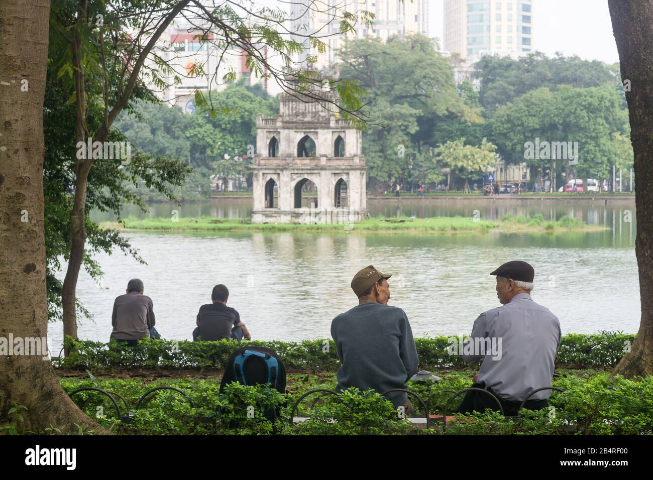 Hanoi Turtle Tower - People chatting near Hoan Kiem Lake in Hanoi with Turtle Tower in the background. Vietnam, Southeast Asia. Stock Photo