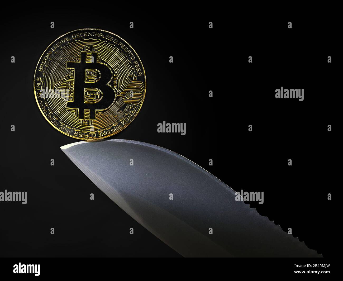 golden bitcoin coin on knife blade isolated on black background with copy space Stock Photo