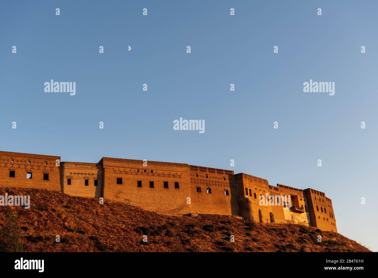 Iraq, Iraqi Kurdistan, Arbil, Erbil. View of the Qalat citadel at sunset. In the backgroun, the moon is shining. Stock Photo