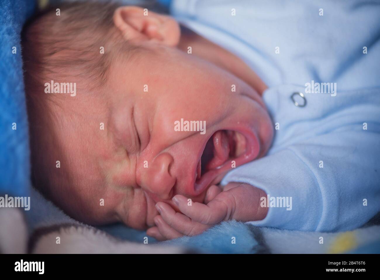 Close up portrait of a newborn baby boy crying in the bed Stock Photo