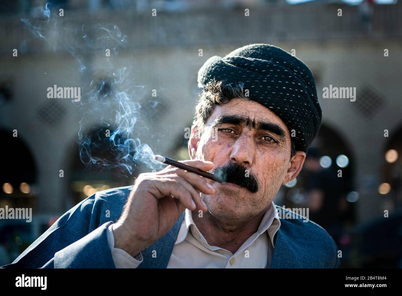 Iraq, Iraqi Kurdistan, Arbil, Erbil. Portrait of a iraqi kurdish man on the park Shar. Smoke from his cigarette is coming out from his mouth. He's wea Stock Photo