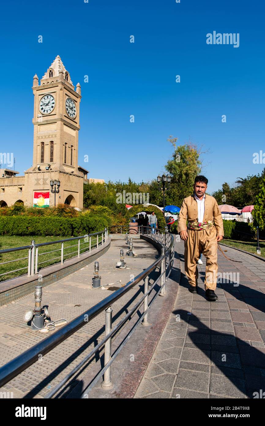 Iraq, Iraqi Kurdistan, Arbil, Erbil. On the park Shar an iraqi kurdish man is walking an alley dressed in traditional kurdish clothes. In the backgrou Stock Photo