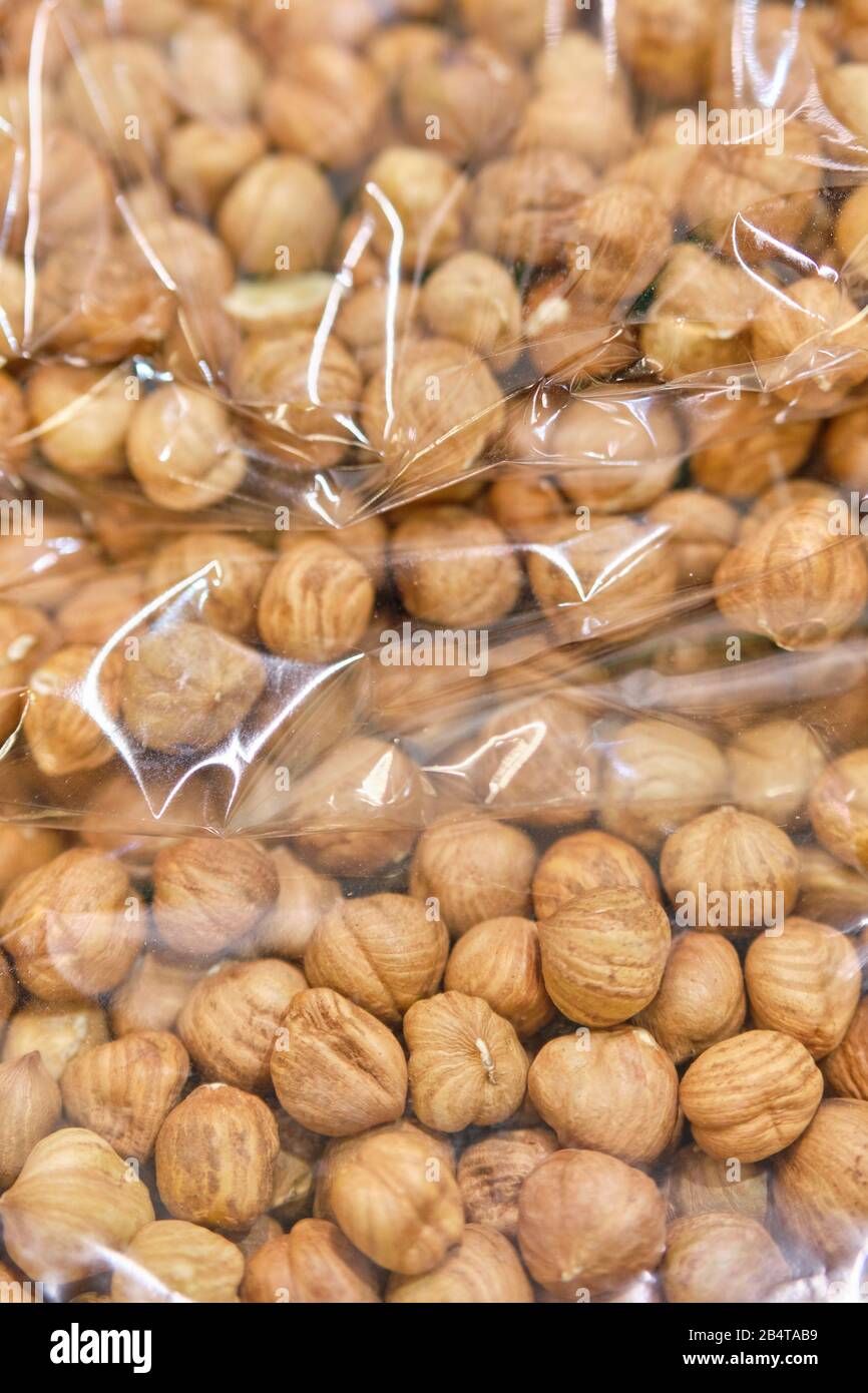 Packing from a transparent bag with peeled hazelnuts. Close up. Vertical. Stock Photo