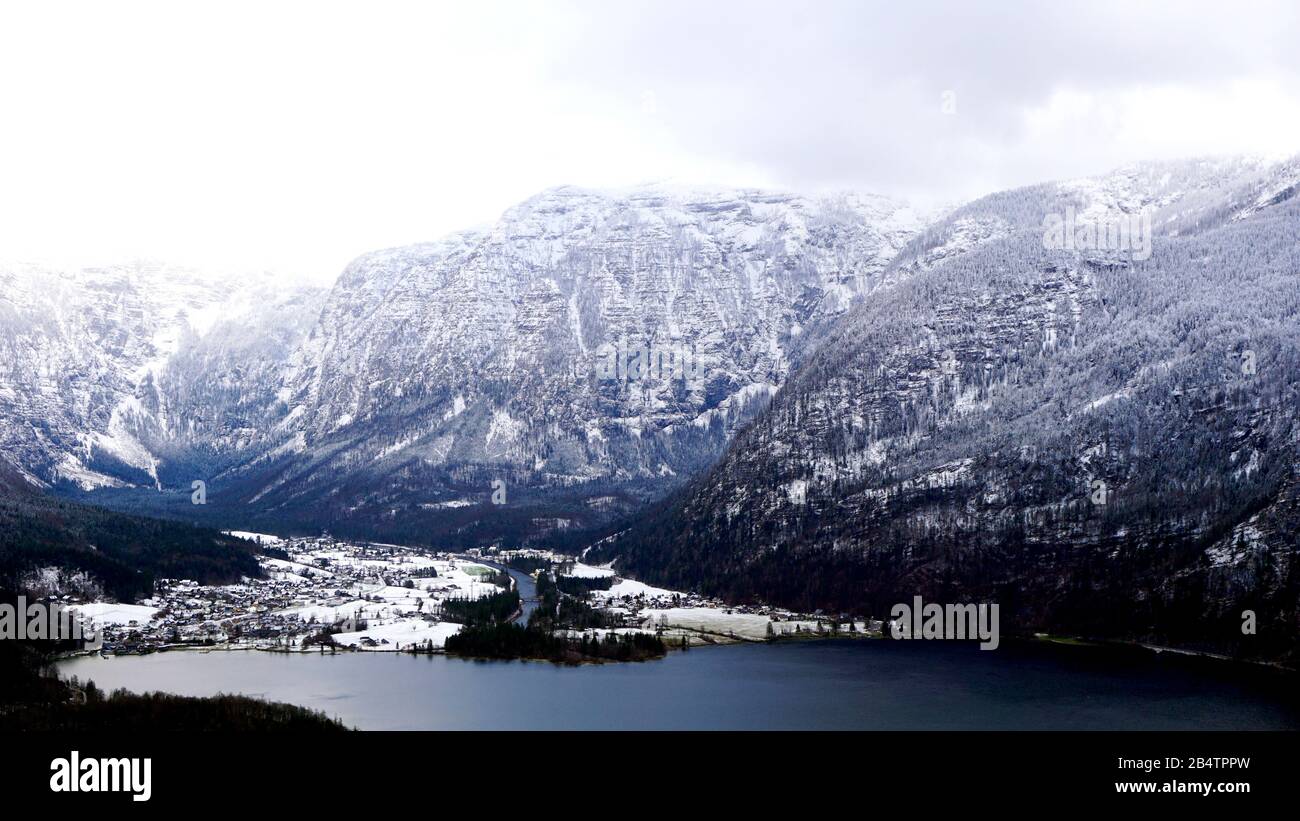 Hike epic mountains outdoor adventure and view of Hallstatt Winter snow mountain landscape and lake through the pine forest in upland valley Stock Photo