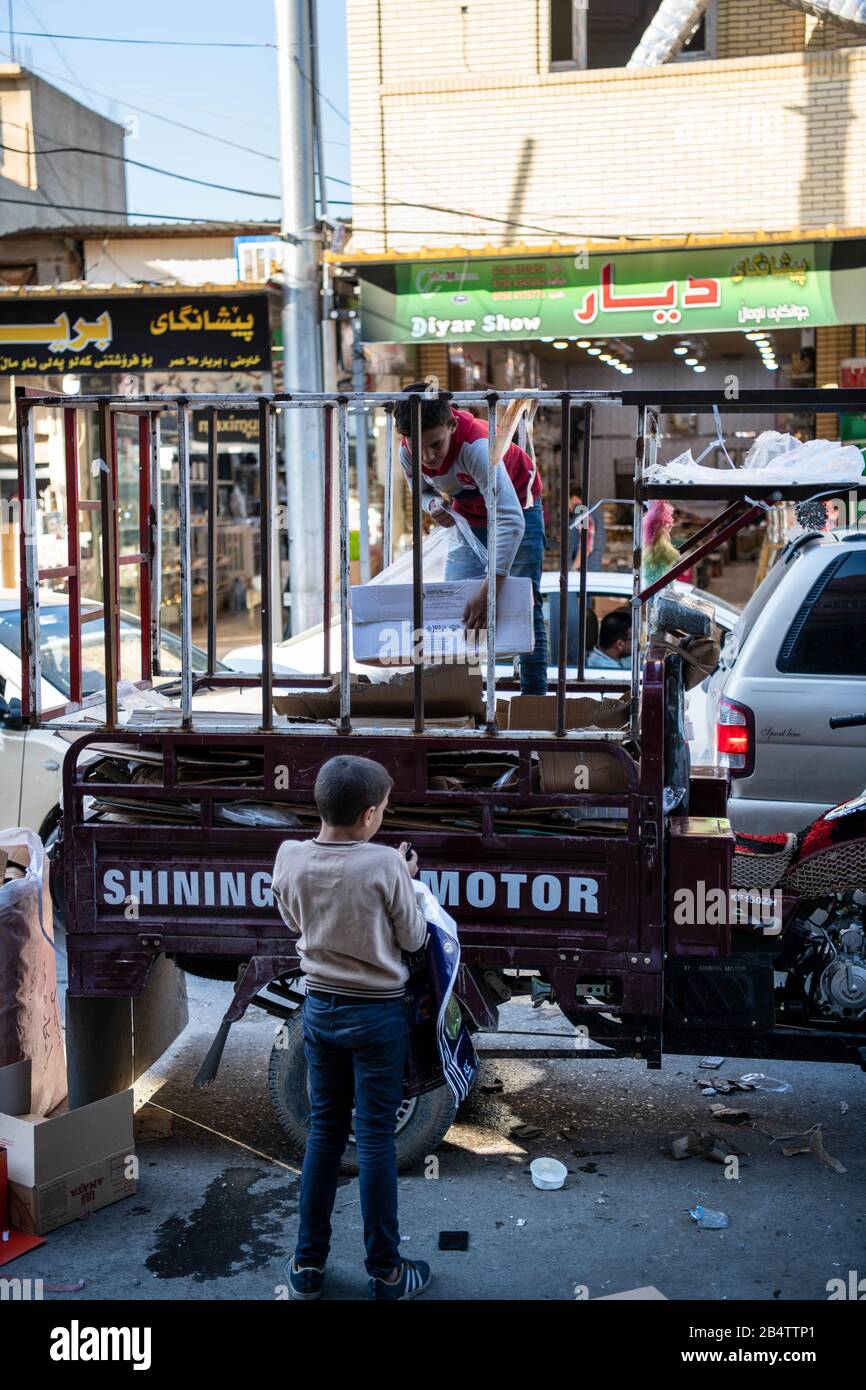 Iraq, Iraqi Kurdistan, Arbil, Erbil. two kids are playing in front of each other. One is standing on the trolley attached at the back of a motorbike. Stock Photo