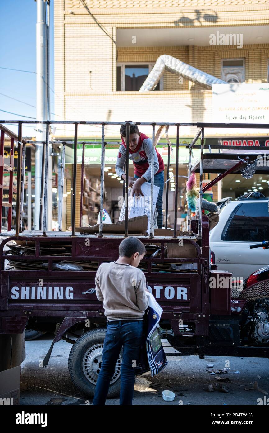 Iraq, Iraqi Kurdistan, Arbil, Erbil. two kids are playing in front of each other. One is standing on the trolley attached at the back of a motorbike. Stock Photo