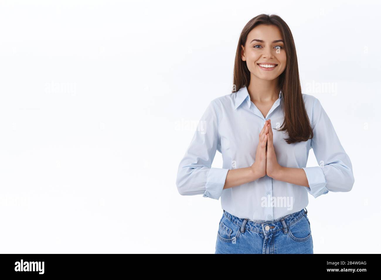 Positivity, people and lifestyle concept. Relieved happy pretty young woman in blue blouse, clasp hands together near chest in pray gesture, smiling Stock Photo