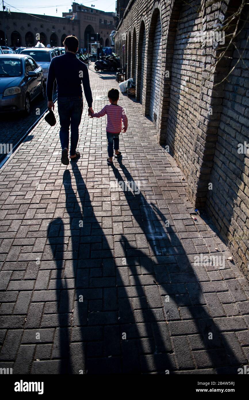 Iraq, Iraqi Kurdistan, Arbil, Erbil. Down Qalat citadel, a father is walking with his kid. Strong shadows are in the foreground Stock Photo