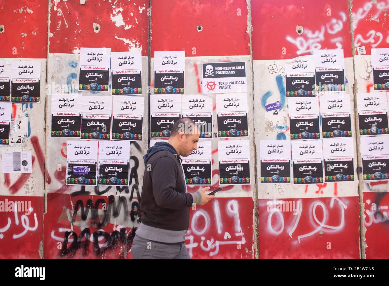 Beirut, Lebanon. 7 March 2020: A pedestrian walks past new anti government posters are glued on a concrete barrier outside Parliament by anti government protesters campaigning against government. corruption. Credit: amer ghazzal/Alamy Live News Stock Photo