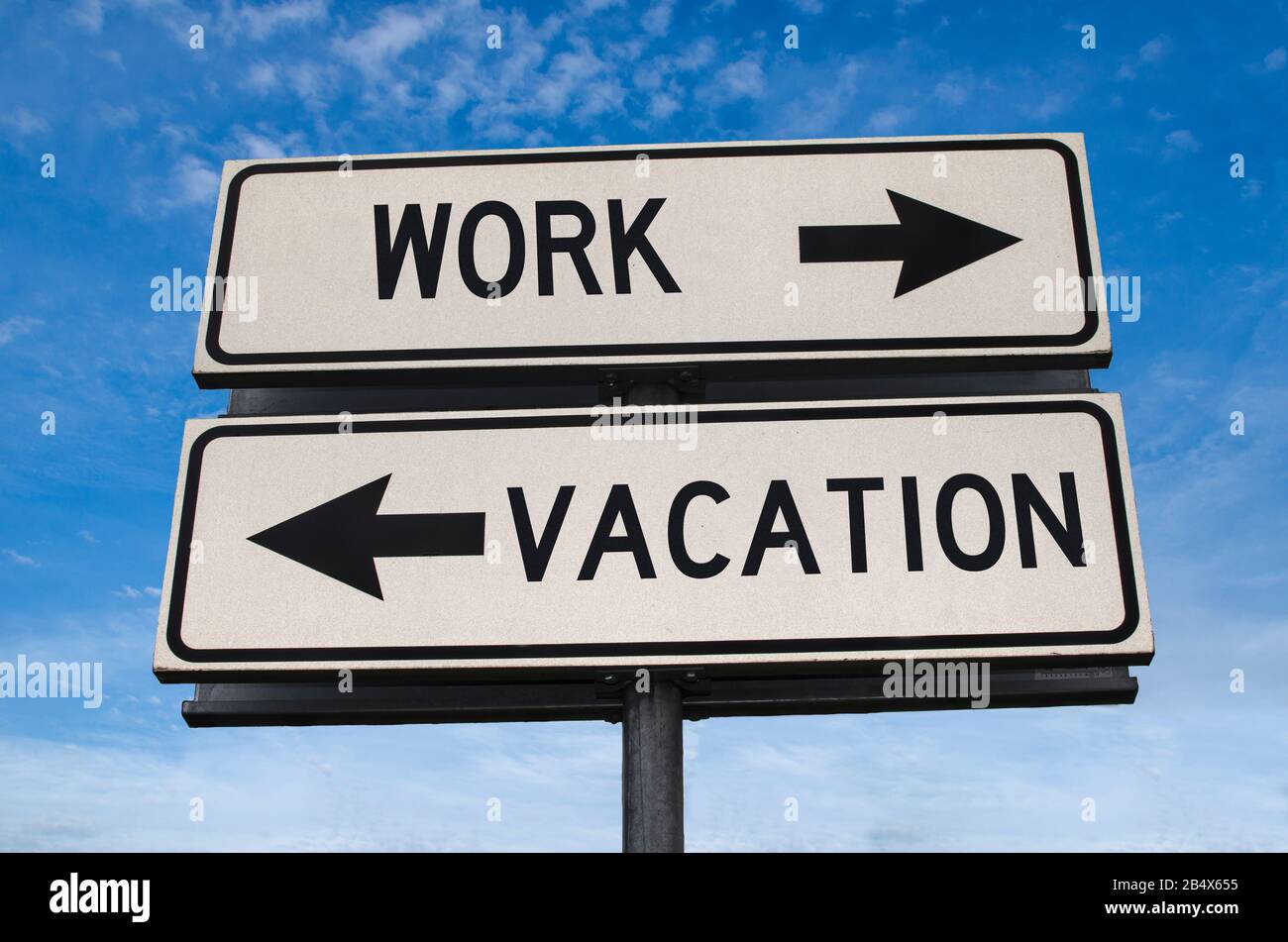 Work vs vacation. White two street signs with arrow on metal pole with word. Directional road. Crossroads Road Sign, Two Arrow. Blue sky background. Stock Photo