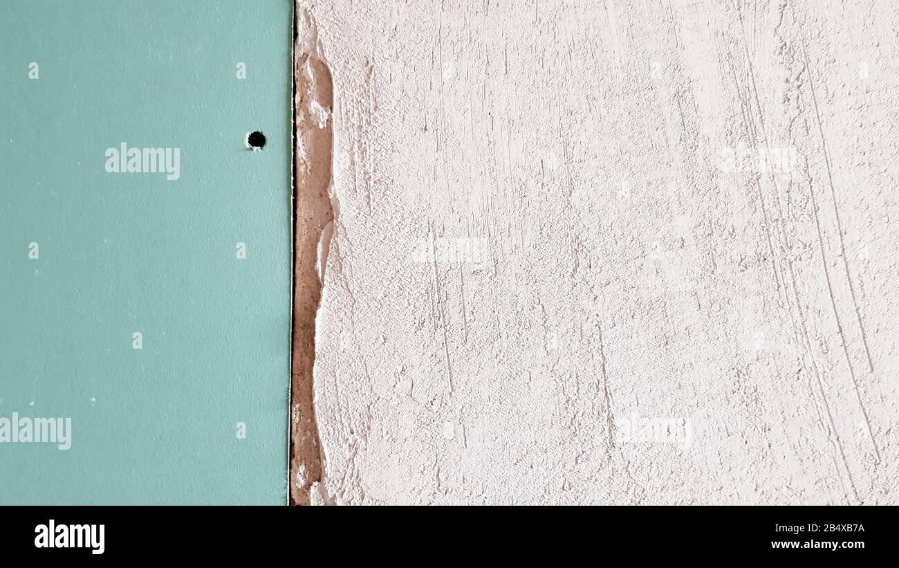 Unfinished wall in a building under construction made of plasterboard. Part of the wall is sheathed with drywall. Drywall is bolted to the wall in ant Stock Photo
