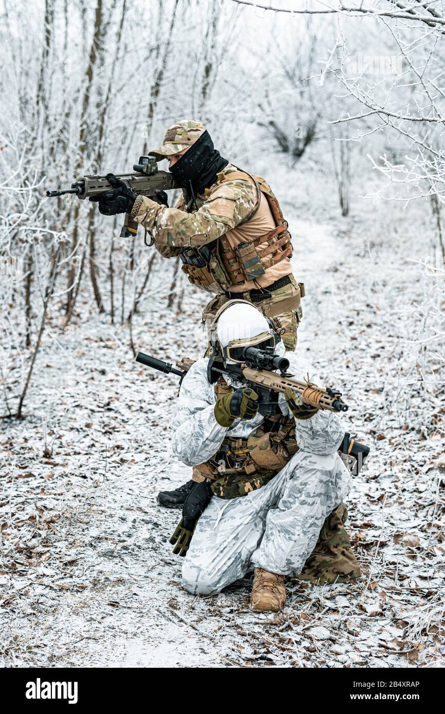 Two airsoft man in camouflage white green uniform back to back with  machinegun. Soldier in the winter forest. Vertical photo Stock Photo - Alamy