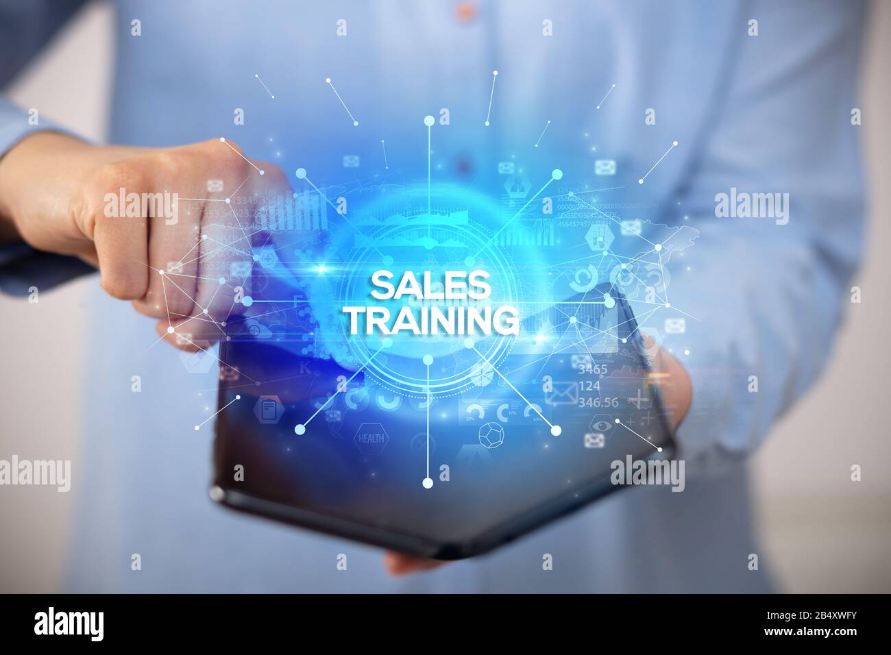 Businessman holding a foldable smartphone with SALES TRAINING inscription, new business concept Stock Photo
