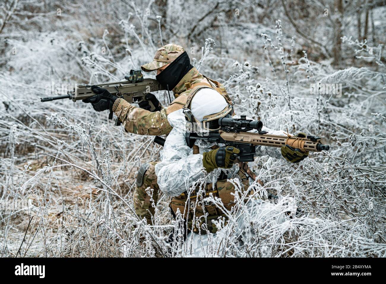 Airsoft man in white camouflage uniform with machinegun. Soldier stood on  knelt in the winter forest and aims at the sight of the machinegun. Side vi  Stock Photo - Alamy
