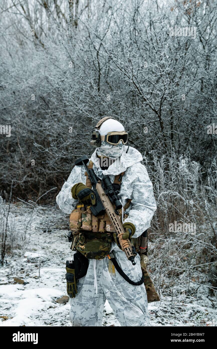 Airsoft man in white camouflage uniform with machinegun. Soldier