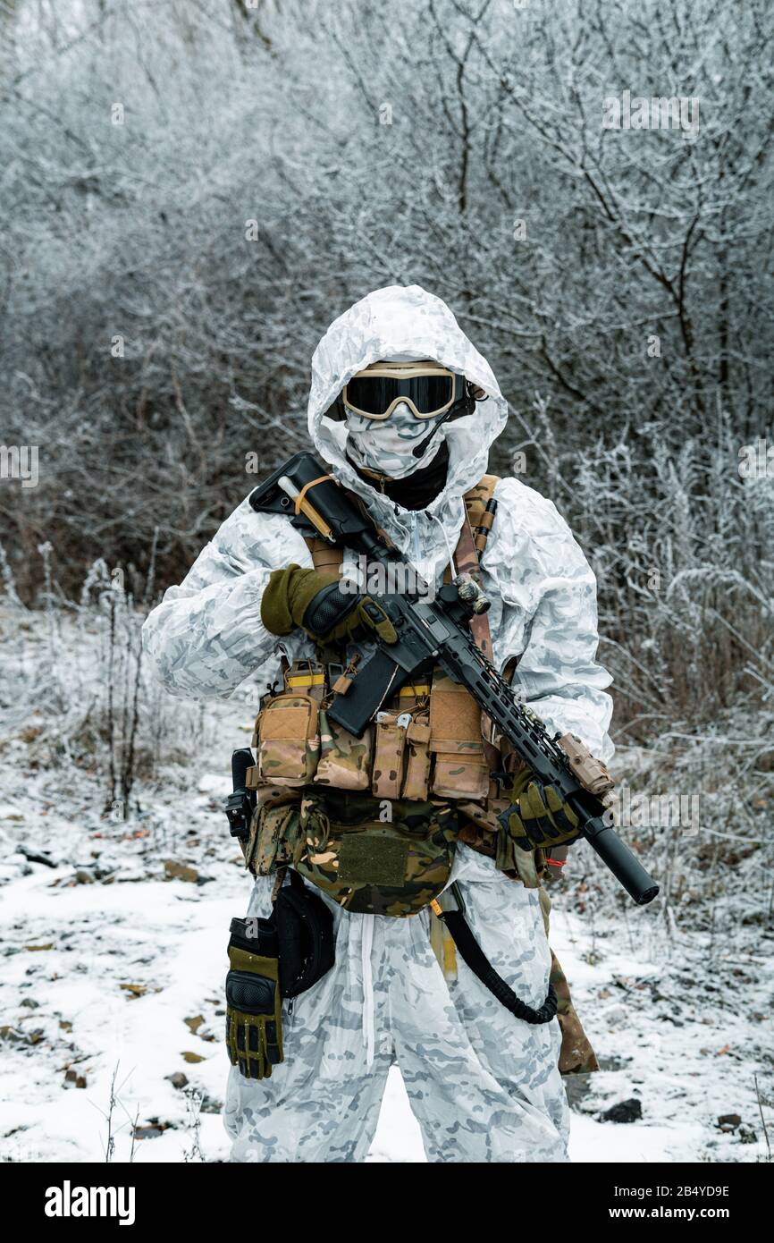 Military man in white camouflage uniform with machinegun. Soldier in the  winter forest territory background. Vertical photo Stock Photo - Alamy