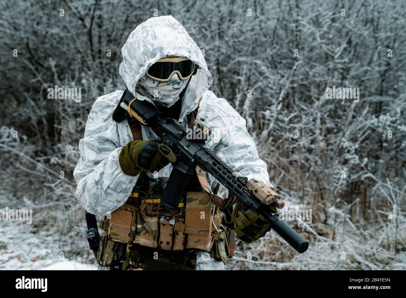 Closeup military man in white camouflage uniform with hood and machinegun.  Horizontal photo side view Stock Photo - Alamy