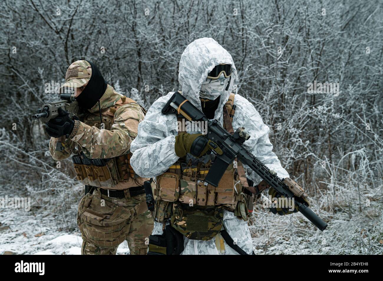 Airsoft man in white camouflage uniform with machinegun. Soldier stood on  knelt in the winter forest and aims at the sight of the machinegun. Side vi  Stock Photo - Alamy