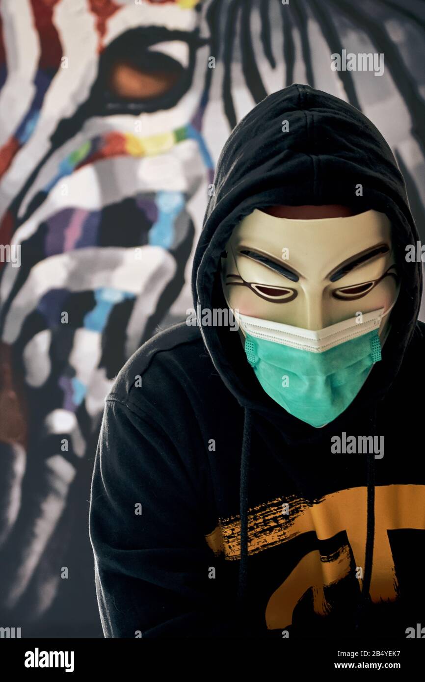 Rastatt/ Germany - March 07 2020: Anonymous hacktivist wearing a medical mask against coronavirus and other diseases and epidemics. Activist hacker Stock Photo