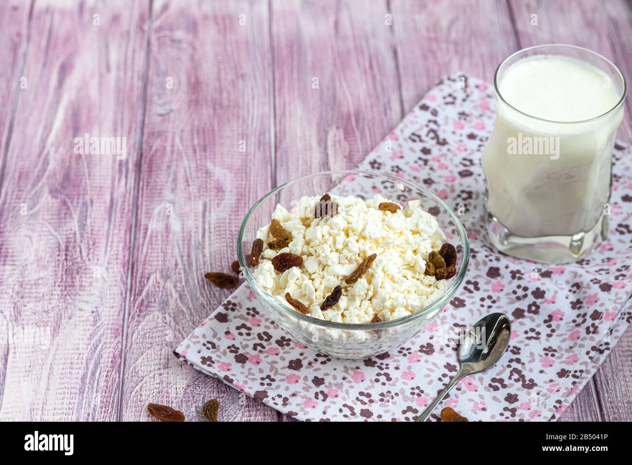 Fresh cottage cheese in a transparent bowl with raisins. In the