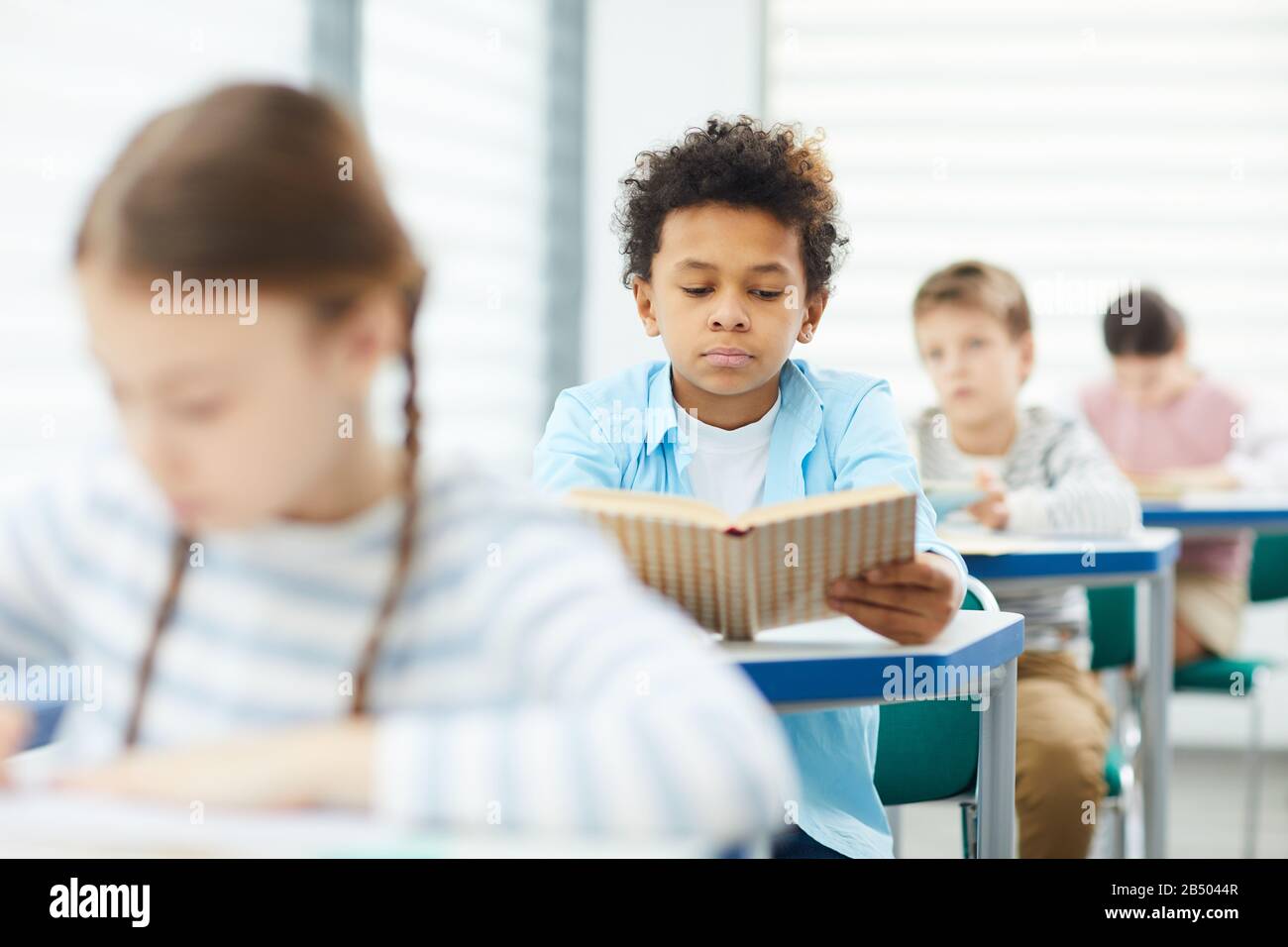 Horizontal medium portrait of twelveyearold boy sitting at desk in
